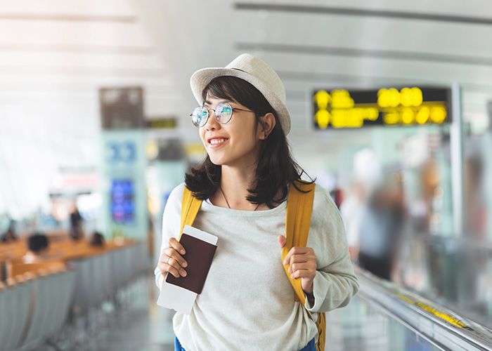 A woman with passport in one hand walking through an airport